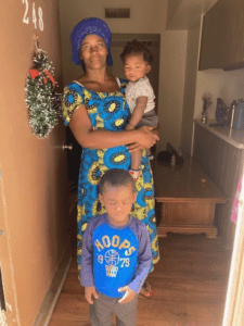 Woman standing in doorway holding infant, small child standing in front of them