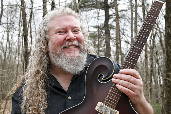 A picture of Joe Jencks holding a guitar.