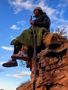 Ceyshe Napa sitting on a cliff with a blue sky background