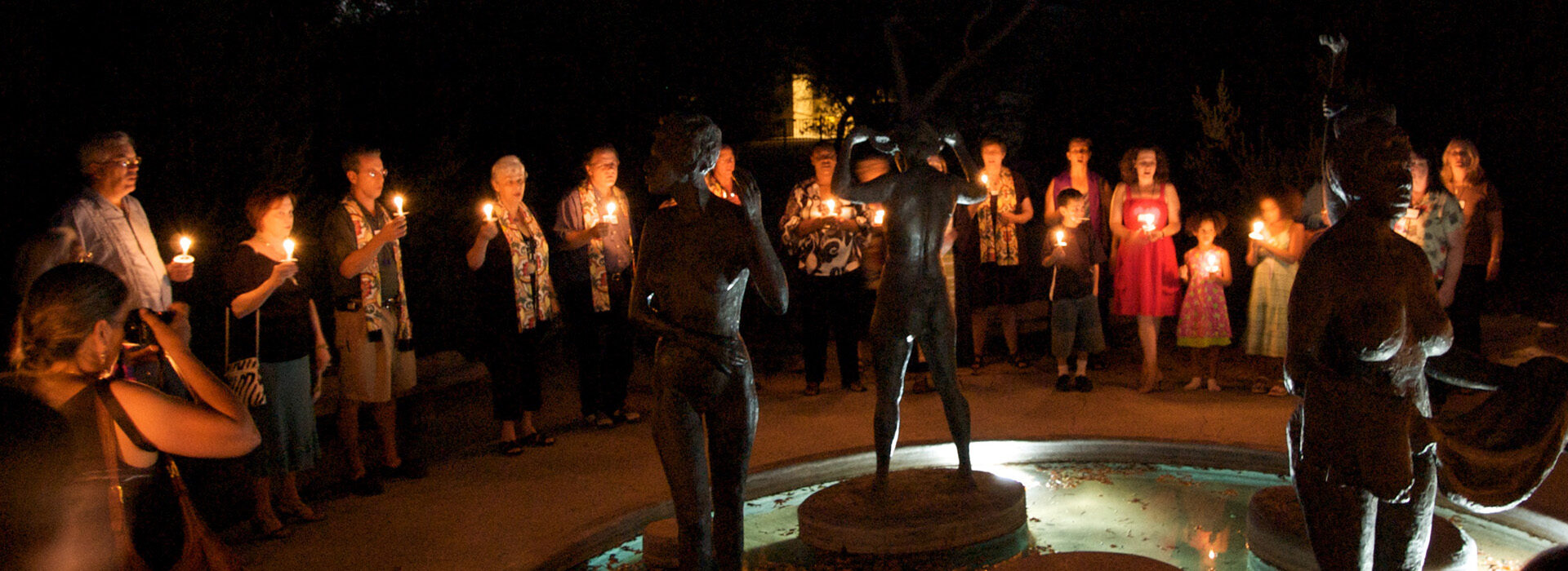 Congregants holding lighted candles in Statuary garden