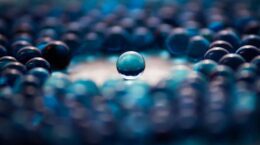 bluish marbles on a flat surface, with one solitary marble in the middle, separate from the others