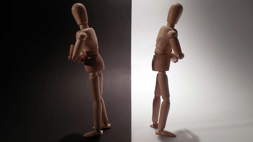 Split screen with 2 wooden puppets standing back to back, arms crossed