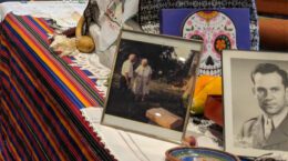 A Dia de los Muertos altar containing personal photos, a picture of a skull and other decorations.