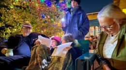 A picture of people celebrating the holidays near a decorated tree.