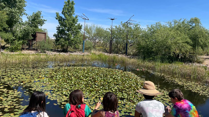 A group of kids sitting near a pond on the liberty wildlife hike