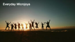 A group of people jumping up and down on the beach with a sunset in the background.