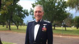 A photo of Roy Miller in military dress with a row of trees behind him.