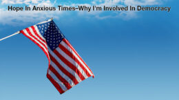 The american flag with a blue sky background and small clouds at the top