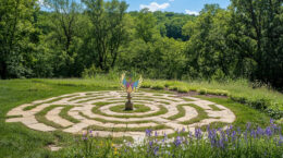 The UUCP Phoenix sits on top of a pedestal at the center of a UU labyrinth with trees in the background.